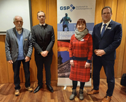 Vier Personen posieren für ein Gruppenfoto vor einem Banner der Gesellschaft für Sicherheitspolitik (GSP).