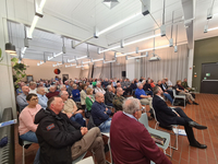 Ein großes Publikum bei einer Veranstaltung in einem Saal, mit einigen Personen in Militäruniformen.