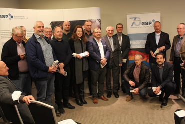 Eine Gruppe von Personen, darunter eine Frau, posiert stehend und hockend bei einer Veranstaltung der Gesellschaft für Sicherheitspolitik.