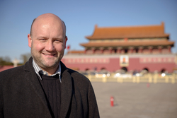 Ein lächelnder Mann vor dem Tor des Himmlischen Friedens in Peking.