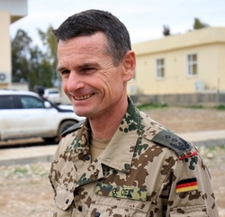 Lächelnder deutscher Brigadegeneral G. Oes in Wüstentarnuniform im Freien.