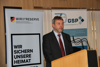 Mann spricht an einem Pult, dahinter Banner des Reservistenverbandes der Bundeswehr und der GSP für Sicherheitspolitik.