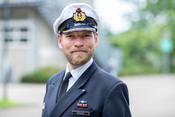 Porträt eines Mannes in deutscher Marineuniform mit weißer Mütze, Bart und Namensschild 'BRAKE'.