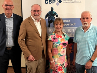 Vier Personen, zwei Männer, eine Frau und ein älterer Mann, posieren lächelnd vor einem GSP-Banner.
