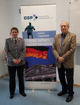 Eine Frau in Bundeswehruniform und ein Mann stehen vor einem Banner der Gesellschaft für Sicherheitspolitik (GSP).