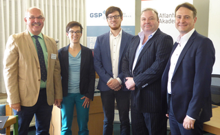 Fünf lächelnde Personen stehen nebeneinander vor Bannern einer Veranstaltung mit den Logos GSP und Atlantik.