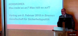 Mann präsentiert Vortrag über Nordkorea. Folie zeigt 'NORDKOREA: Was treibt es an? Was hält es auf?' und Datum 8. Februar 2018 in Bremen.