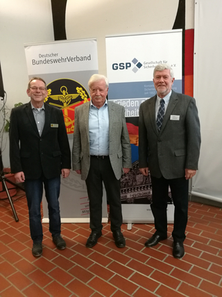 Drei Männer stehen vor Bannern des Deutschen BundeswehrVerbandes und der Gesellschaft für Sicherheitspolitik.