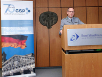 Deutscher Militäroffizier spricht am Rednerpult im Bonifatiushaus. Ein GSP-Banner mit Reichstagsgebäude ist sichtbar.