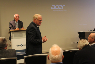 Ein Redner gestikuliert bei einer Präsentation mit einem GSP-Podium und einem Acer-Logo an der Wand.