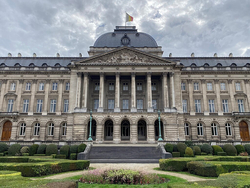 Königlicher Palast Brüssel, ein neoklassizistisches Gebäude mit Kuppel, Säulen und belgischer Flagge, umgeben von Gärten.