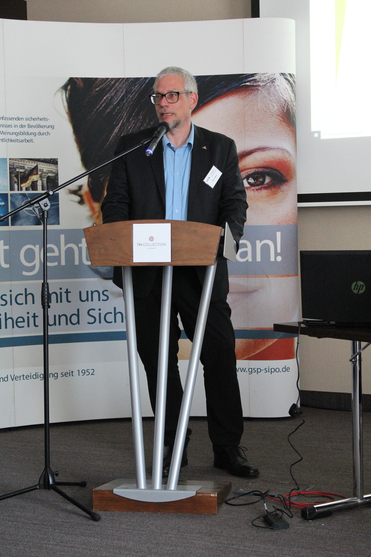 Oliver Meer spricht an einem Rednerpult vor einem NH Collection Banner während einer Präsentation.