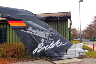 Leitwerk eines schwarzen modernen Jets mit deutscher Flagge, einem Doppeldecker und dem Namen 'Boelcke' in weißer Schrift.