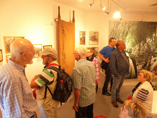 Gruppe von Menschen in einer Ausstellung, die verschiedene historische Exponate an den Wänden betrachten.
