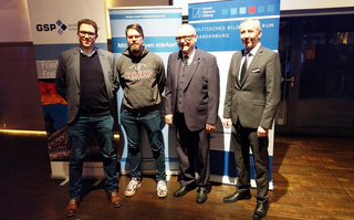 Vier Männer vor Bannern der GSP, des Reservistenverbandes und der Konrad-Adenauer-Stiftung.