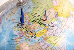 Globus mit NATO/EU- und Russland-Flaggen und militärischen Miniaturen, die geopolitische Spannungen in Europa und Asien darstellen.
