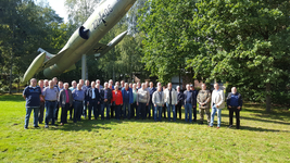 Eine Gruppe von etwa 40 Personen posiert vor einem Lockheed F-104 Starfighter Kampfflugzeug in einem Park.