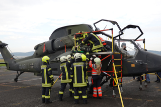 Rettungsübung: Feuerwehrleute und Rettungskräfte bergen eine Person aus dem Cockpit eines Militärhubschraubers.