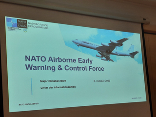 Eine Präsentationsfolie mit dem Titel 'NATO Airborne Early Warning & Control Force' und einem NATO AWACS Flugzeug.