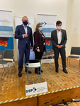 Drei maskierte Personen auf einer Bühne bei einer Veranstaltung der Gesellschaft für Sicherheitspolitik (GSP).