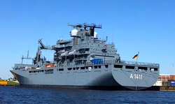 Deutsches Marineversorgungsschiff FGS Berlin (A1411) im Hafen, von Steuerbord-Heck mit deutscher Flagge unter blauem Himmel.