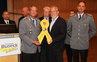 Zwei Männer, einer in Uniform, halten gelbes Band 'Solidarität mit unseren Soldatinnen und Soldaten' bei einer Veranstaltung in Buseck.