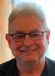 Porträt eines lächelnden Mannes mittleren Alters mit grauen Haaren und Brille.