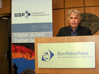 Mann spricht am Rednerpult mit GSP- und Bonifatiushaus-Schildern im Hintergrund.