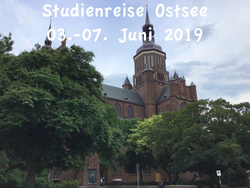 Historische Backsteinkirche, teilweise von Bäumen verdeckt. Text: 'Studienreise Ostsee 03.-07. Juni 2019'.