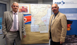 Zwei Männer in Anzügen stehen vor einer Korea-Karte und GSP-Sicherheitspolitik-Bannern mit deutschen und nordkoreanischen Flaggen.