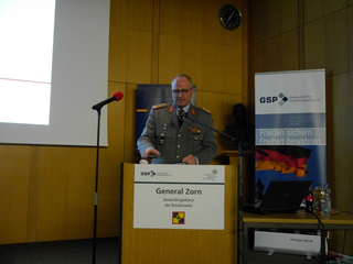 General Zorn, Generalinspekteur der Bundeswehr, spricht an einem Rednerpult mit GSP-Bannern.