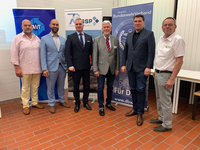 Sechs Männer posieren für ein Foto bei einer Veranstaltung mit Bannern von DWT, GSSP und Deutschem BundeswehrVerband.