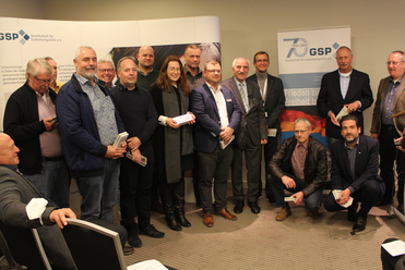 Gruppenfoto von Mitgliedern der Gesellschaft für Sicherheitspolitik e.V. bei einer Veranstaltung, einige halten kleine Geschenke.