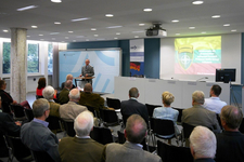 Ein Soldat hält einen Vortrag vor Publikum in einem Konferenzraum mit einer Präsentation über NATO und Litauen.