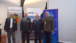 Vier Männer, darunter ein Uniformierter, posieren vor Bannern des BundeswehrVerbandes, der GSP und der DWT.