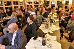 Eine große Gruppe von Menschen nimmt an einer Veranstaltung in einem hell beleuchteten Restaurant oder Saal teil.
