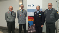 Vier Männer in Uniformen, darunter drei in Bundeswehr-Uniformen, stehen vor einem Banner der GSP (Gesellschaft für Sicherheitspolitik).