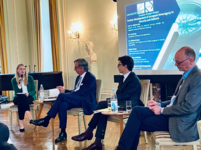 Podiumsdiskussion zu europäischer Souveränität und Sicherheit mit Sprecherin und Panelisten, vor Präsentationsleinwand.