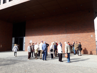 Eine Gruppe von Menschen, hauptsächlich Senioren, vor dem modernen Backsteingebäude des BND unter einem dunklen Vordach.