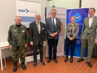 Fünf lächelnde Personen, darunter ein Soldat, vor Bannern von GSP, BundeswehrVerband und DWT.