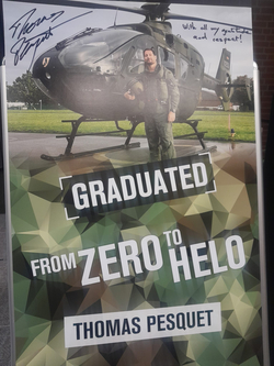 Banner von Astronaut Thomas Pesquet: lächelnder Mann in Pilotenuniform vor Helikopter, Text 'Graduated from Zero to Helo'.