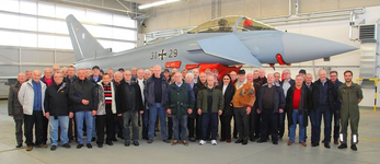 Eine Gruppe von Personen posiert vor einem Eurofighter Typhoon Kampfjet in einem Hangar.