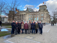 Lachende Senioren posieren vor dem Berliner Reichstagsgebäude mit Kuppel und deutscher Flagge.
