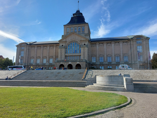 Das Nationalmuseum in Stettin, ein großes historisches Gebäude mit einem Mittelturm und breiten Treppen unter blauem Himmel.
