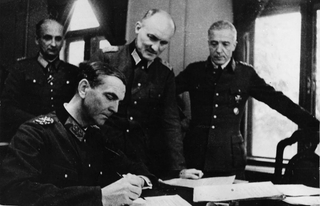 Deutscher General Jodl unterzeichnet die bedingungslose Kapitulationsurkunde in Reims, von Offizieren beobachtet.