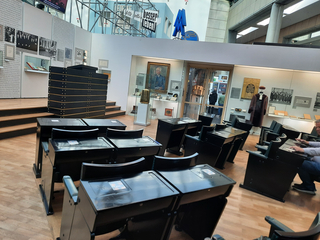 Innenansicht einer Ausstellung mit Reihen von Wahlkabinen oder Pulten, historischen Exponaten und dem Schriftzug "besser leben!".