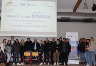 Junge Menschen und Erwachsene posieren vor einer Leinwand mit der Präsentation „Klima, Energie, Wasser“ der GSP Lippstadt.