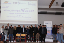 Junge Menschen und Erwachsene posieren vor einer Leinwand mit der Präsentation „Klima, Energie, Wasser“ der GSP Lippstadt.