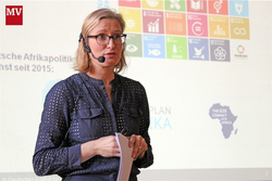 Frau mit Brille und Headset präsentiert zur deutschen Afrikapolitik, UN-SDGs und G20 Compact with Africa.