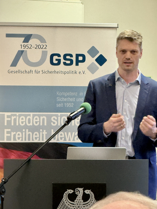 Mann spricht mit geballten Fäusten an einem Pult mit Bundesadler vor einem GSP-Banner zum 70-jährigen Jubiläum (1952-2022).